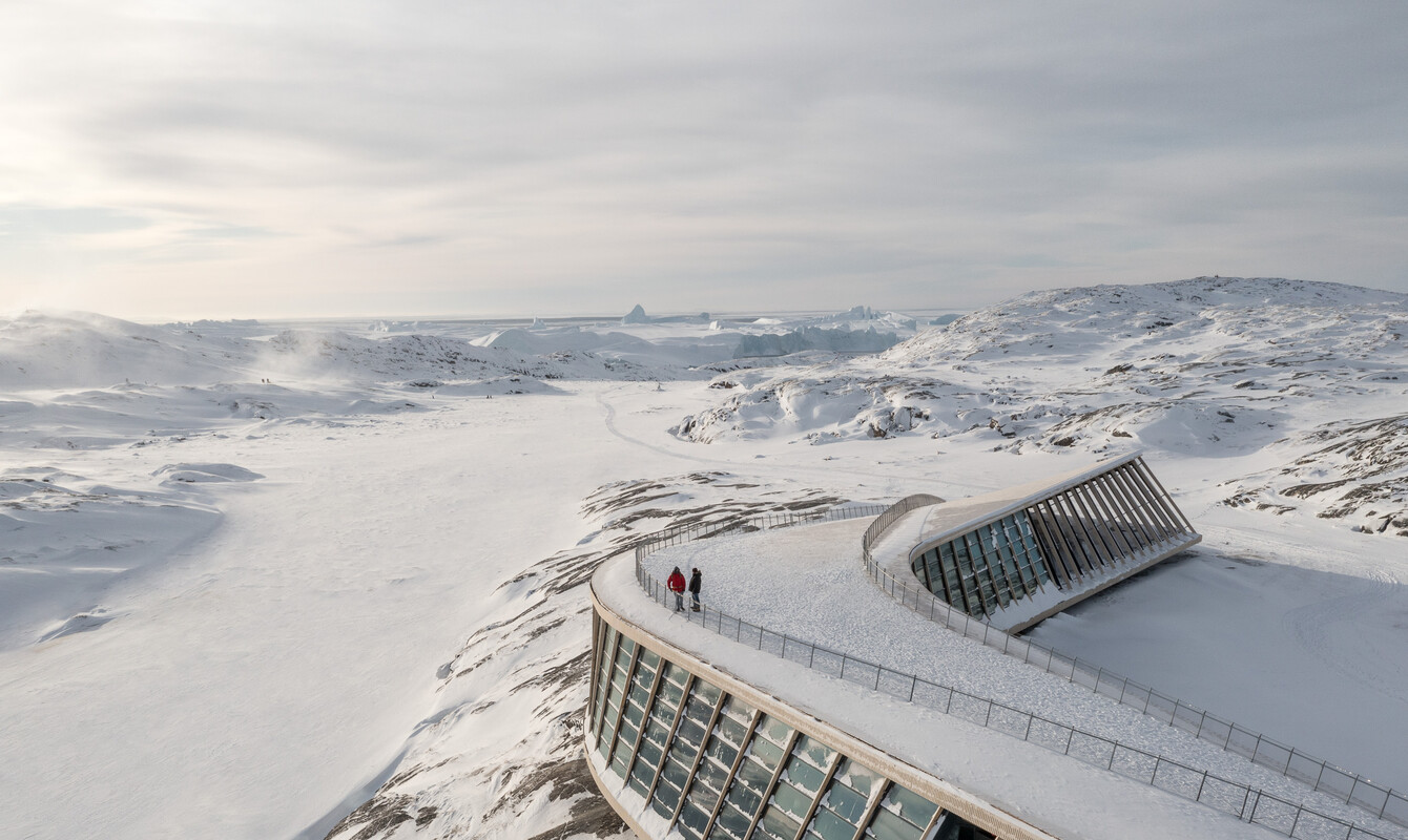 Isfjordscenteret set fra oven med udsigt over Diskobugten og to vandrende på taget